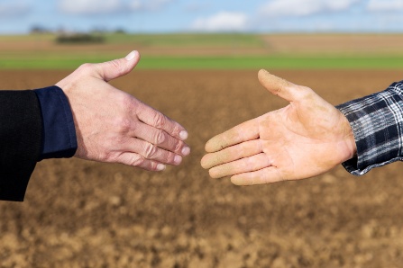 Handschlag zwischen Geschäftsmann und Landwirt vor Acker